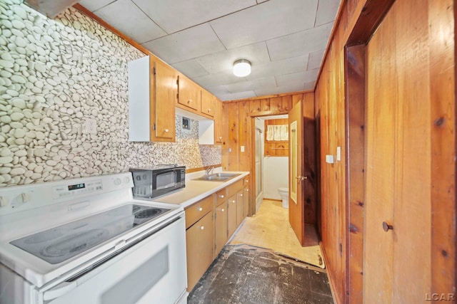 kitchen featuring white range with electric stovetop, wood walls, and sink