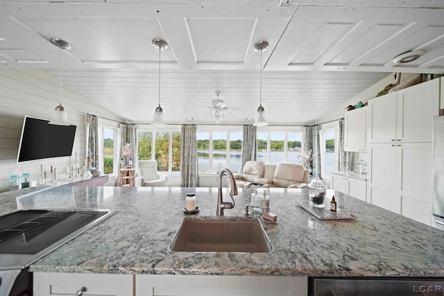 kitchen with white cabinets, light stone countertops, sink, and hanging light fixtures