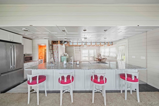 kitchen with a kitchen bar, appliances with stainless steel finishes, a spacious island, pendant lighting, and white cabinets