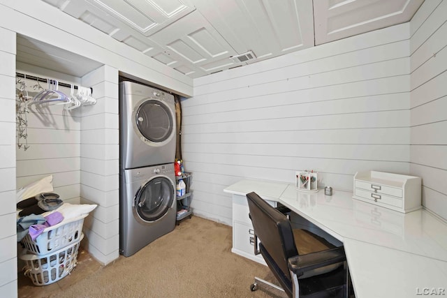 laundry area with wood walls, stacked washing maching and dryer, and light carpet