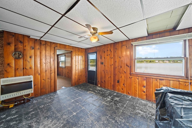 spare room with heating unit, wooden walls, a drop ceiling, and ceiling fan