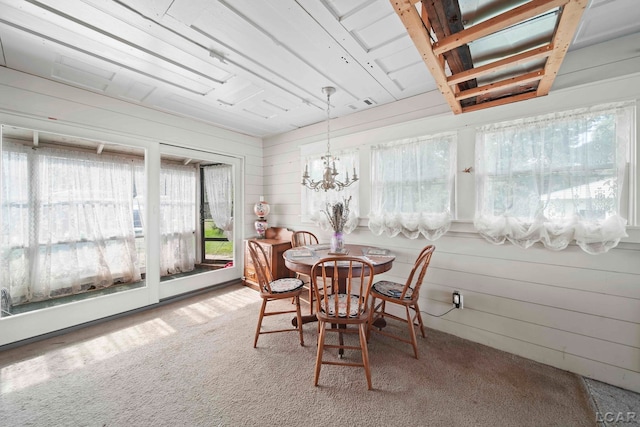 carpeted dining space with a notable chandelier and wood walls