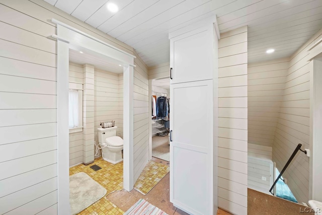 bathroom featuring wooden walls and toilet