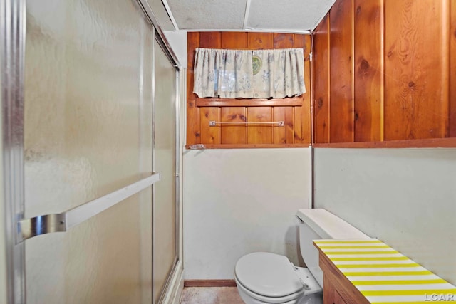 bathroom featuring toilet and a shower with shower door