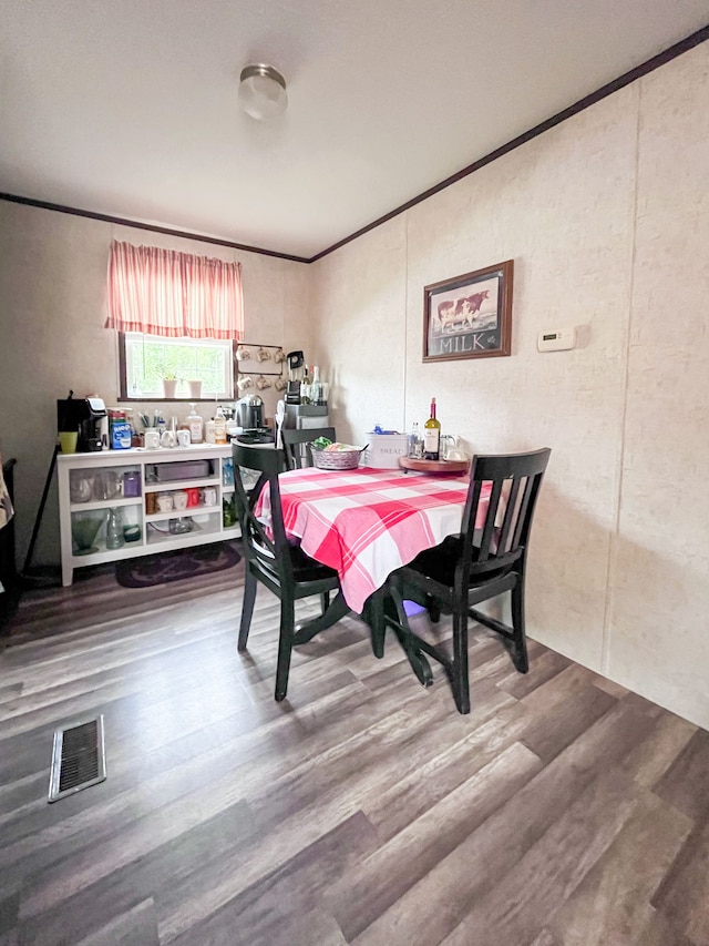 dining space featuring hardwood / wood-style floors and crown molding