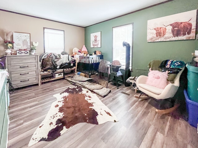 bedroom with crown molding, light hardwood / wood-style flooring, and multiple windows