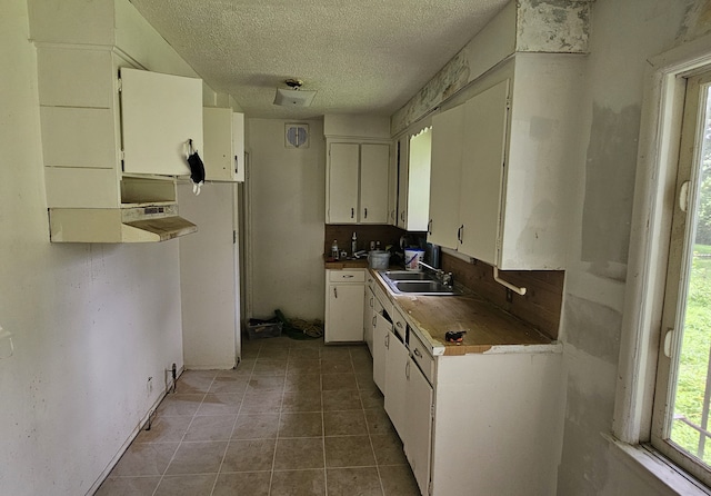 kitchen featuring white cabinets, a textured ceiling, tile patterned flooring, and sink