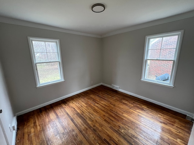 empty room with dark hardwood / wood-style flooring, a wealth of natural light, and ornamental molding