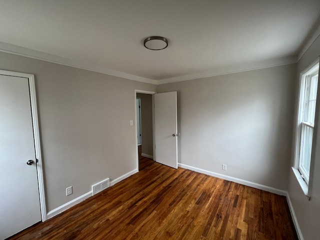 empty room with dark hardwood / wood-style floors and ornamental molding