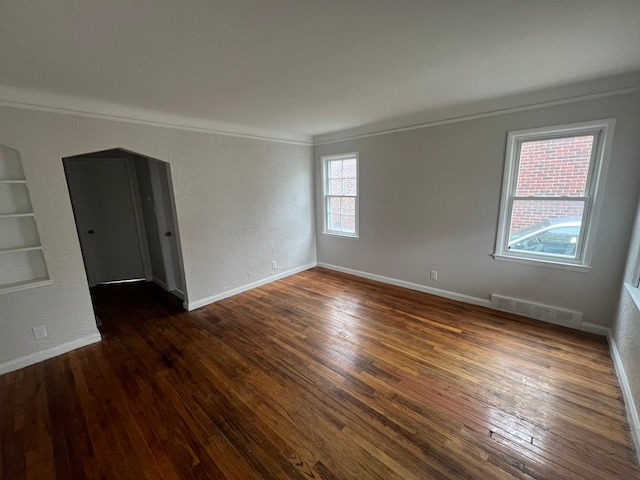 unfurnished room featuring plenty of natural light, dark hardwood / wood-style floors, and ornamental molding