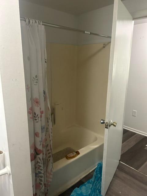 bathroom featuring wood-type flooring and shower / bath combo with shower curtain