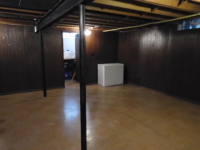 basement with fridge and wooden walls