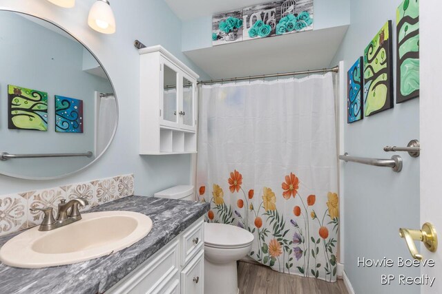 bathroom with wood finished floors, toilet, vanity, and a shower with curtain