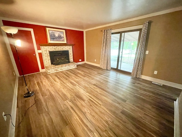 unfurnished living room with hardwood / wood-style floors, a brick fireplace, and ornamental molding