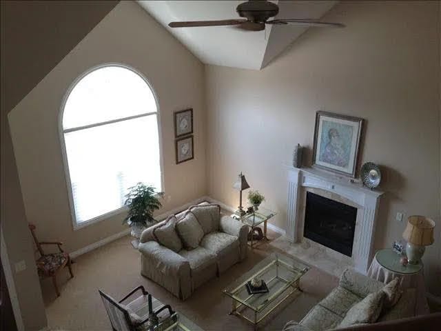 carpeted living room with a premium fireplace, ceiling fan, and lofted ceiling