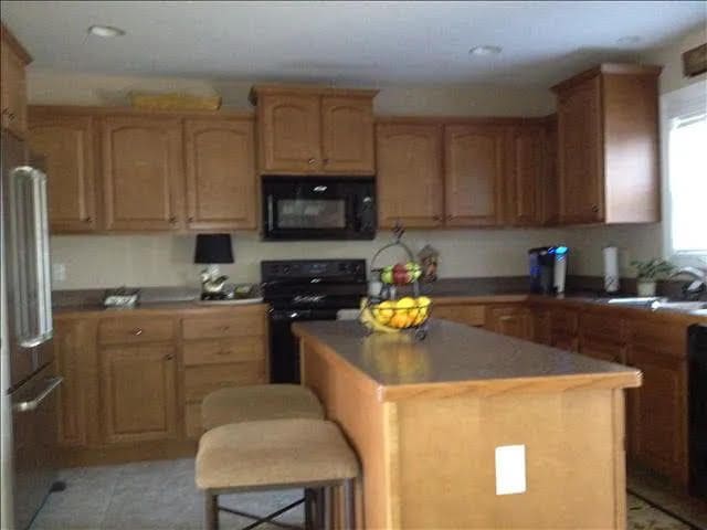 kitchen featuring a breakfast bar, a center island, black appliances, and sink