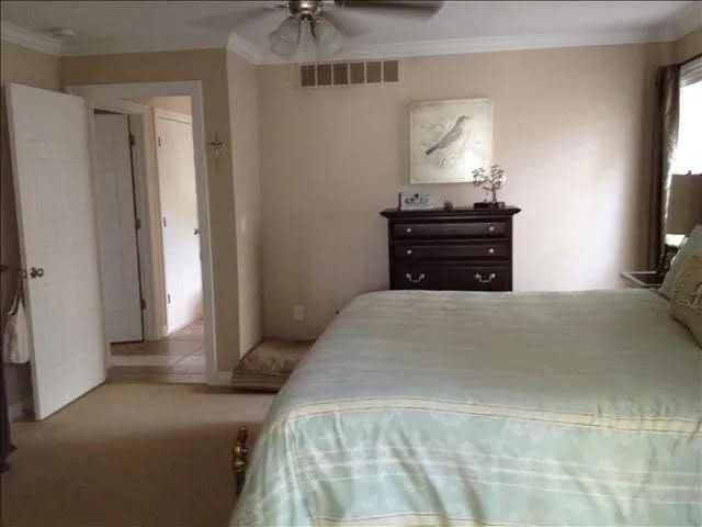 carpeted bedroom with ceiling fan and crown molding