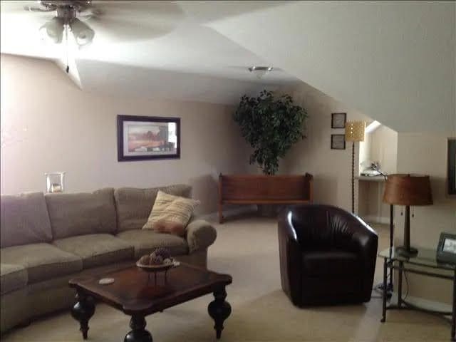 carpeted living room with ceiling fan and lofted ceiling