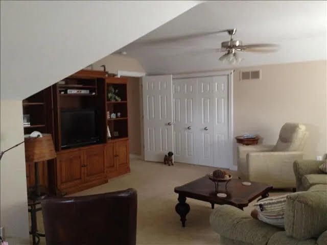 carpeted living room with ceiling fan