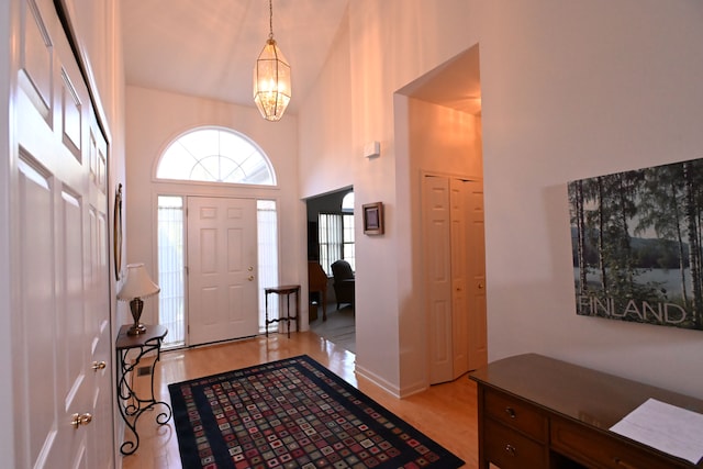 entryway featuring a chandelier, a high ceiling, and light wood-type flooring