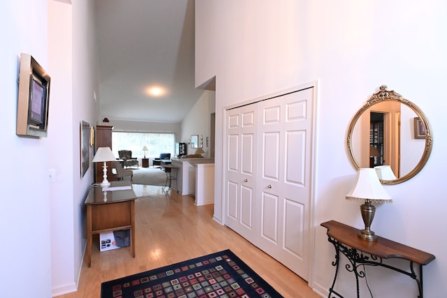 corridor featuring light hardwood / wood-style floors and high vaulted ceiling