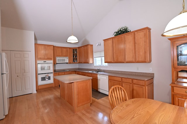 kitchen with pendant lighting, a center island, white appliances, sink, and light wood-type flooring