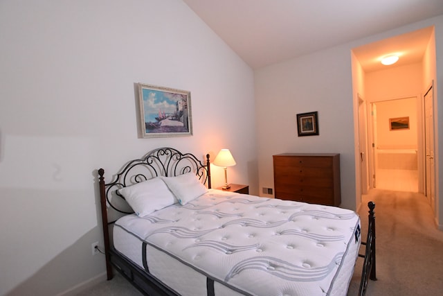 bedroom featuring ensuite bath, carpet floors, and vaulted ceiling