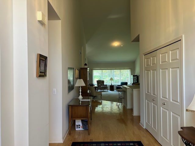 hall featuring a high ceiling and light hardwood / wood-style flooring