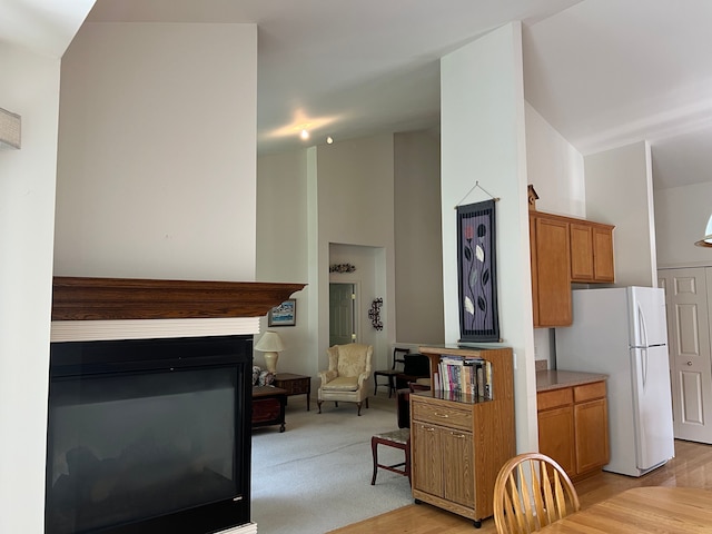 kitchen with a towering ceiling, light wood-type flooring, and white refrigerator