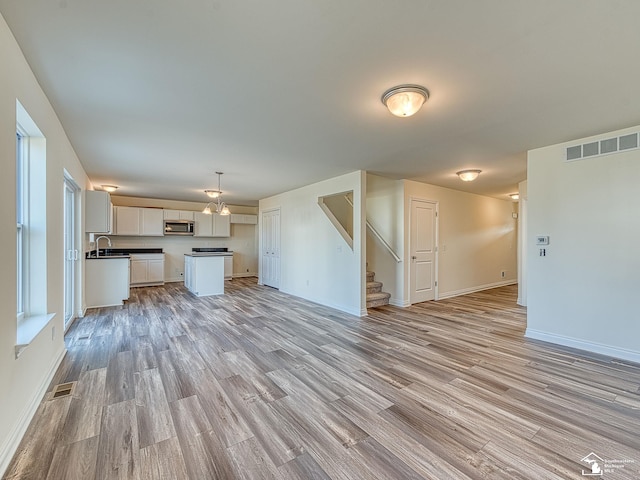 unfurnished living room with sink and light hardwood / wood-style floors