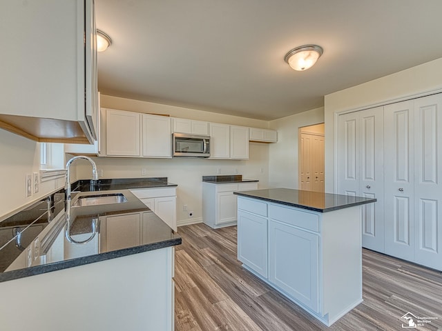 kitchen featuring white cabinetry, sink, a kitchen island, and wood-type flooring