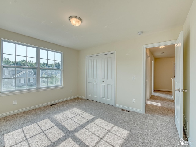 unfurnished bedroom with light carpet and a closet