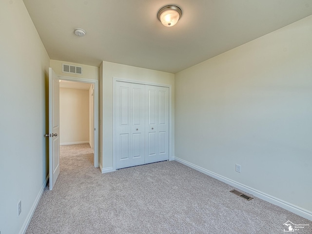 unfurnished bedroom with a closet and light colored carpet