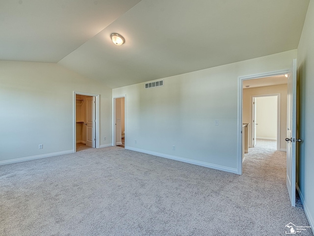 unfurnished bedroom featuring lofted ceiling, light colored carpet, a spacious closet, and a closet