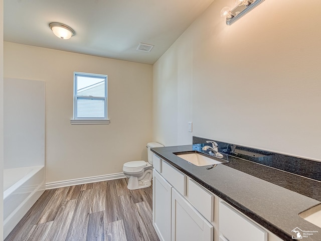 bathroom featuring hardwood / wood-style floors, vanity, toilet, and a washtub