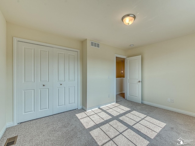 unfurnished bedroom with light colored carpet and a closet