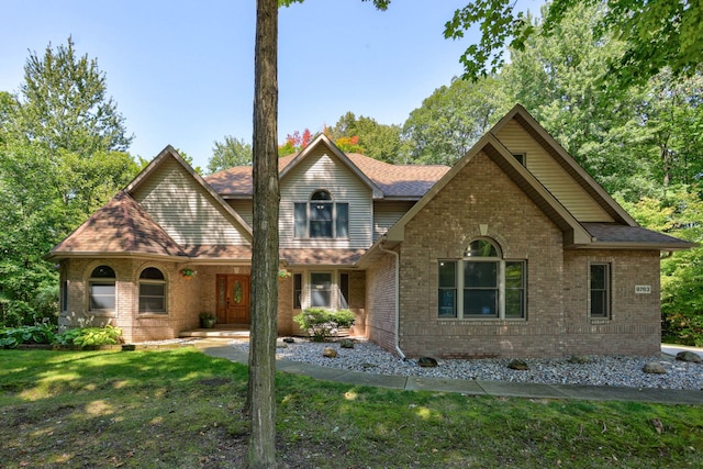 view of front of property with a front yard, brick siding, and roof with shingles