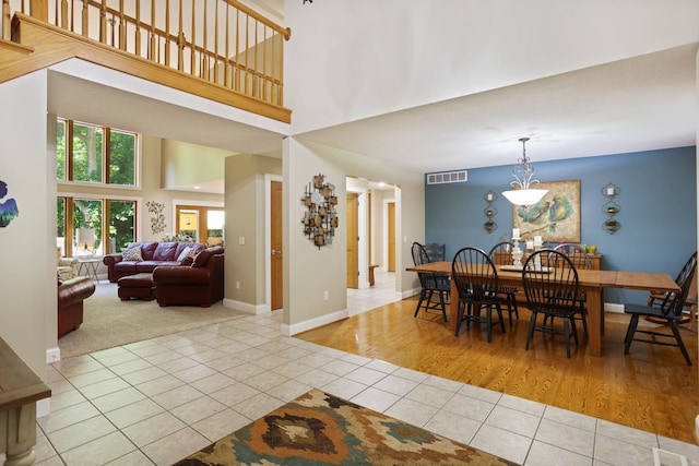 tiled dining space with baseboards, visible vents, and a high ceiling