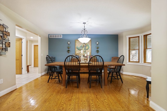 dining space with light wood finished floors, baseboards, and visible vents