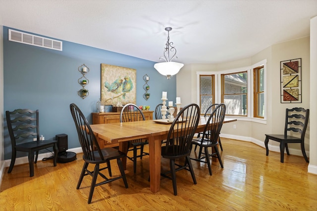 dining area with baseboards, visible vents, and light wood finished floors