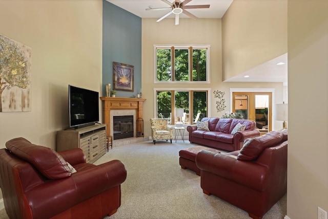 carpeted living area featuring a glass covered fireplace, ceiling fan, and a towering ceiling