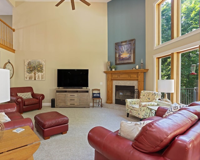 living area with baseboards, a ceiling fan, a towering ceiling, carpet, and a fireplace