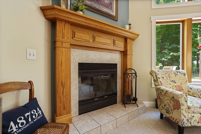 living area featuring a healthy amount of sunlight, a fireplace, light carpet, and baseboards