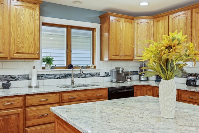 kitchen featuring a sink, light stone counters, backsplash, and dishwasher