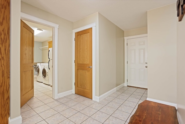 interior space with light tile patterned floors, independent washer and dryer, and baseboards