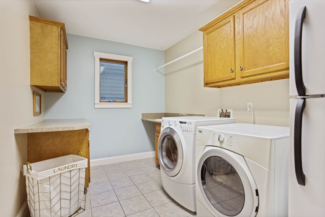 laundry room featuring washing machine and dryer, cabinet space, baseboards, and light tile patterned floors