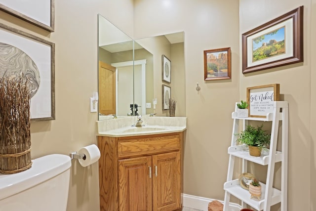 half bath featuring baseboards, vanity, and toilet