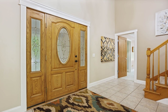 entryway featuring stairs, light tile patterned flooring, and baseboards