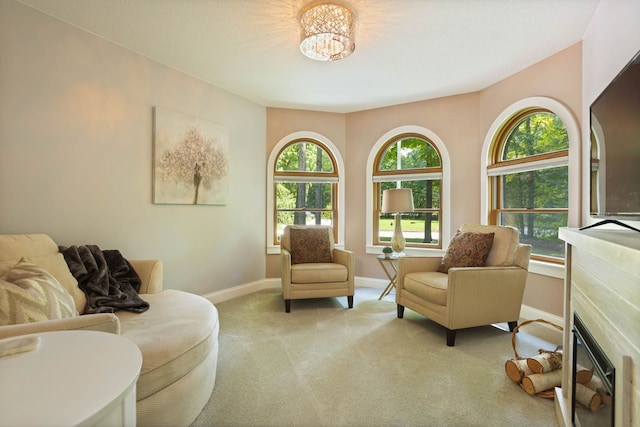 sitting room with carpet, a glass covered fireplace, and baseboards