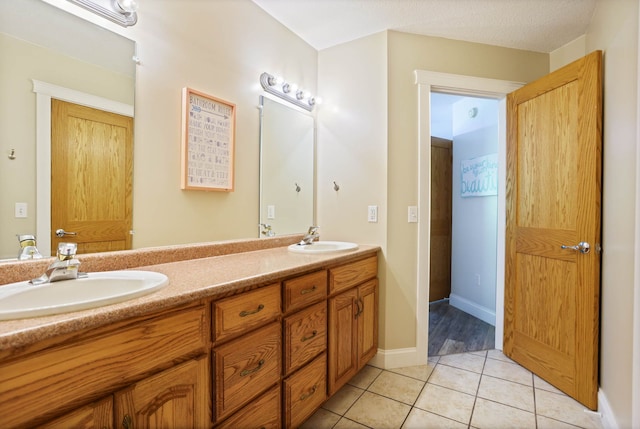 full bathroom featuring tile patterned flooring, a sink, baseboards, and double vanity